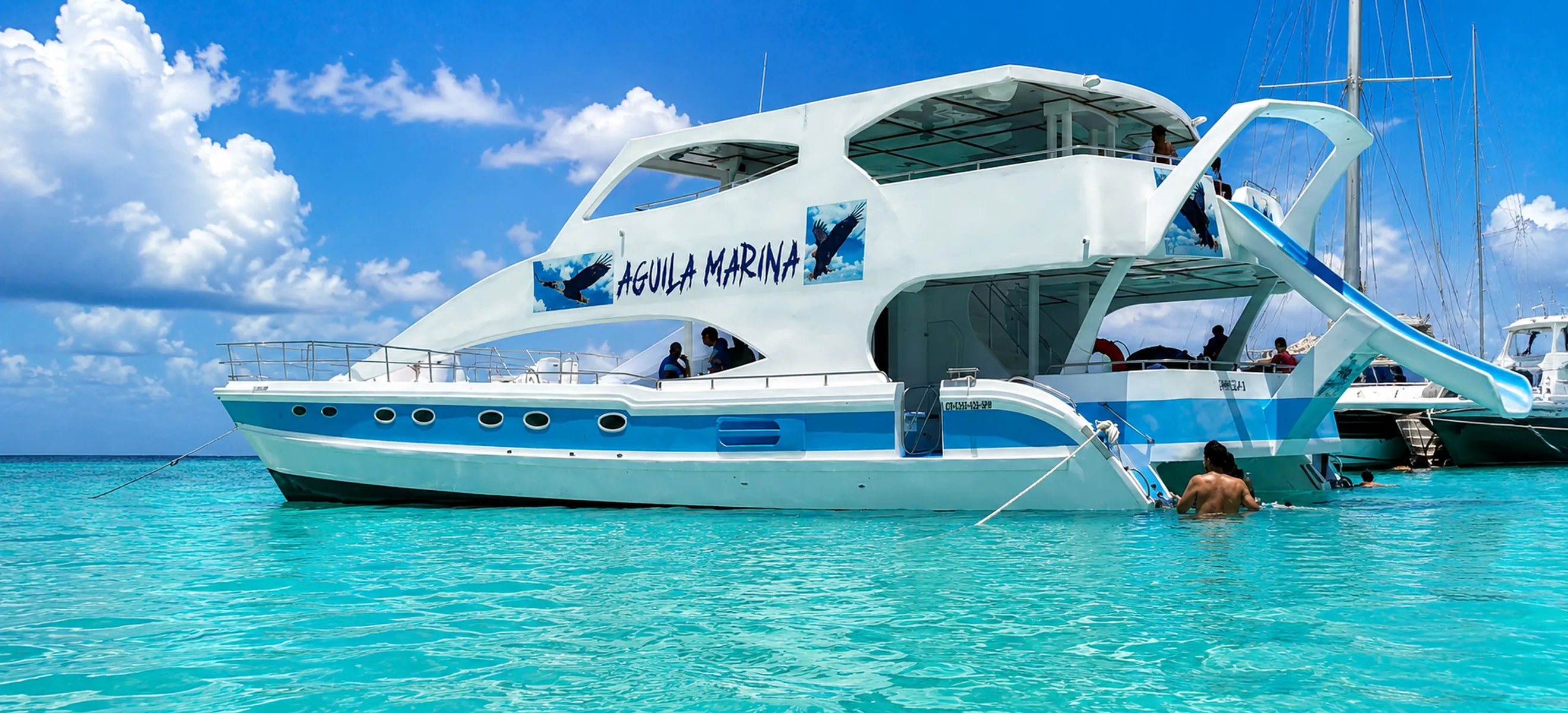Aguila Marina luxury yacht with a waterslide anchored in the crystal-clear turquoise waters of Punta Cana, Dominican Republic, during a private Caribbean yacht charter experience. 