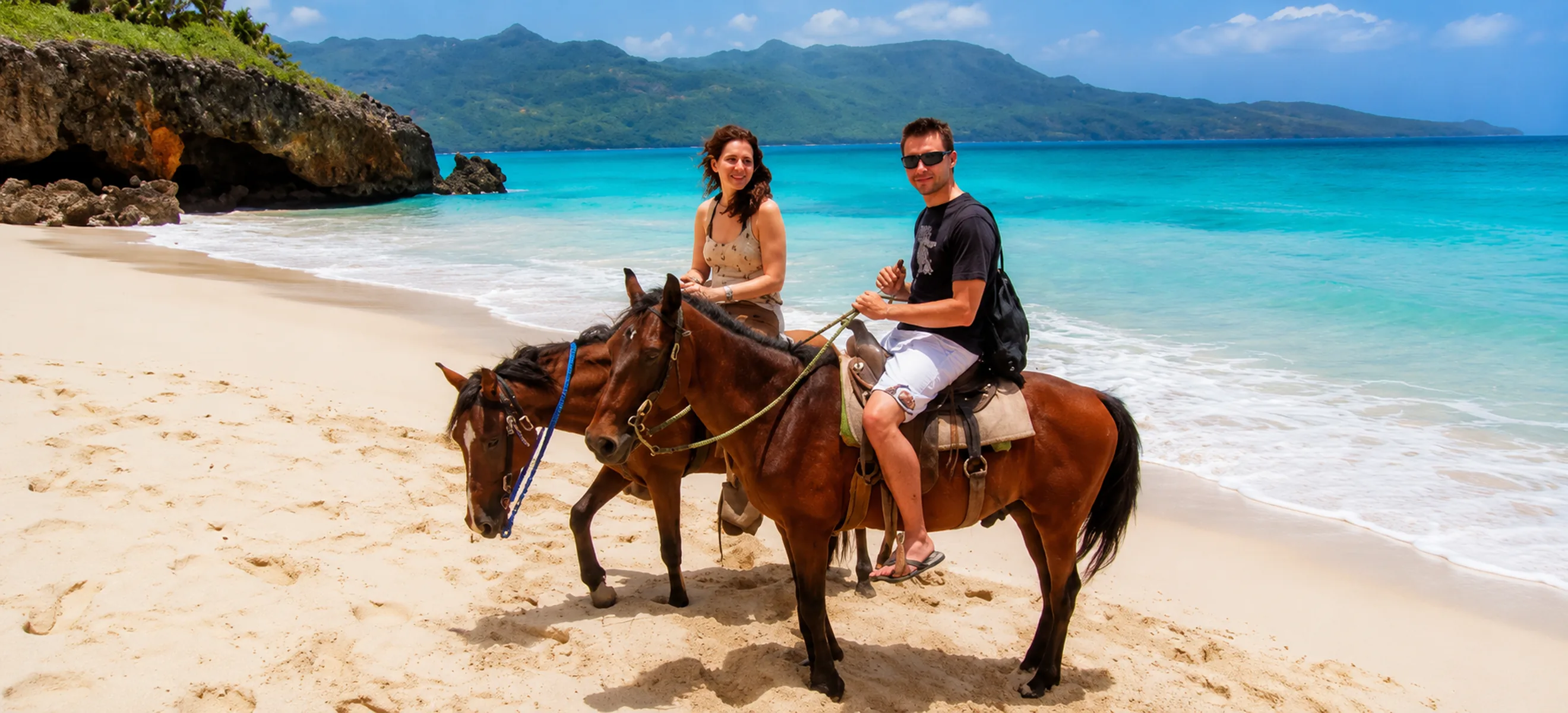 Couple enjoying a romantic horseback riding excursion along the white sand beach in Punta Cana, Dominican Republic.