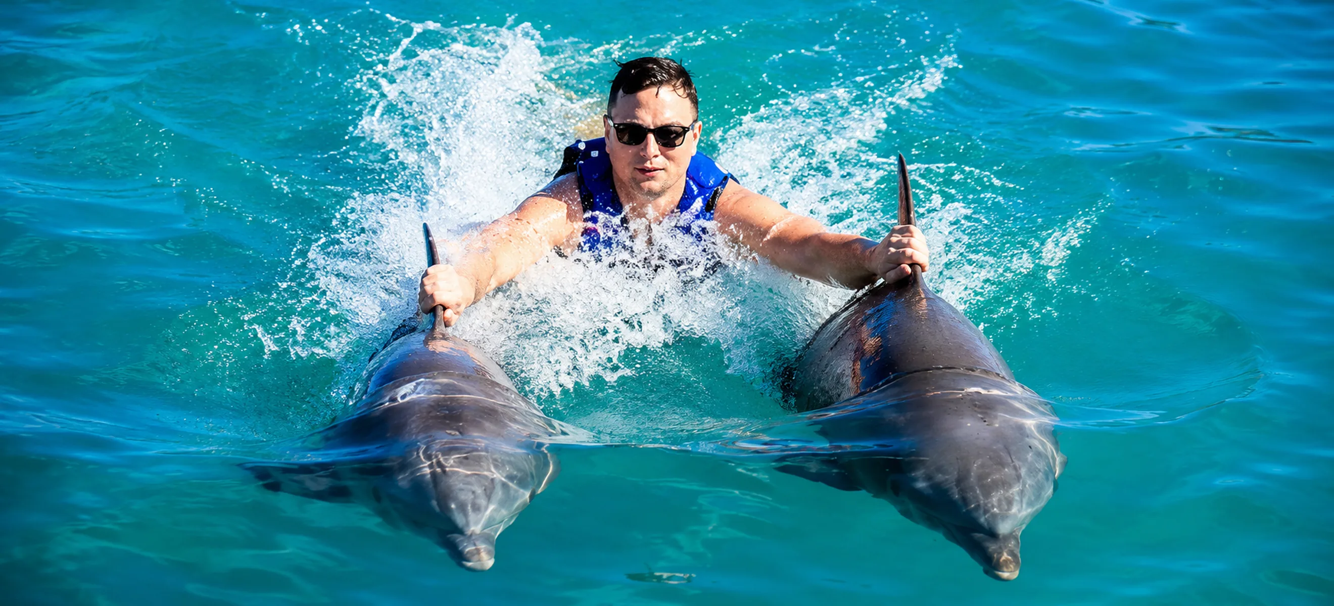 Guest enjoying the Dolphin Excellence dorsal ride with two bottlenose dolphins in Punta Cana, Dominican Republic.