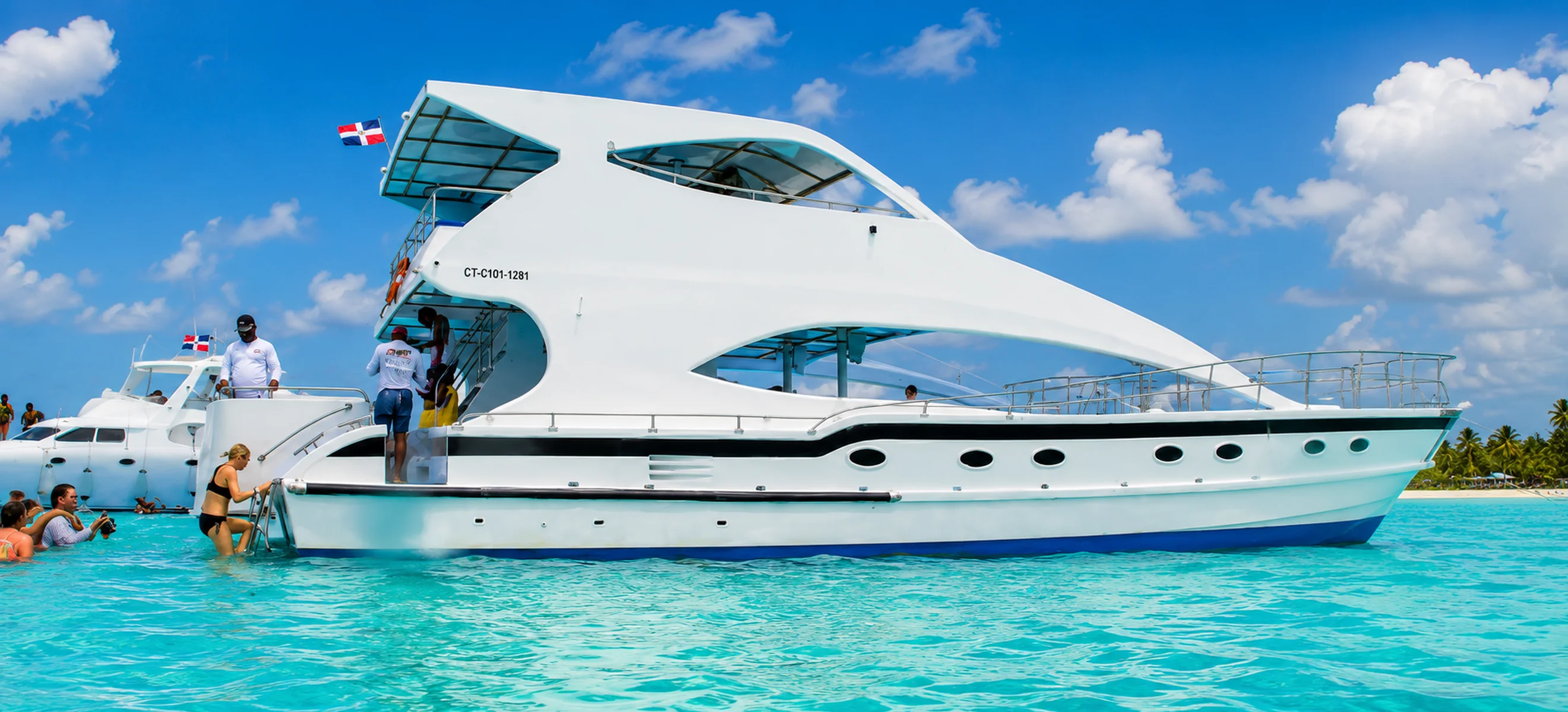 Luxury yacht anchored at the Punta Cana Natural Pool with guests enjoying crystal-clear turquoise Caribbean waters during a private yacht charter in the Dominican Republic.