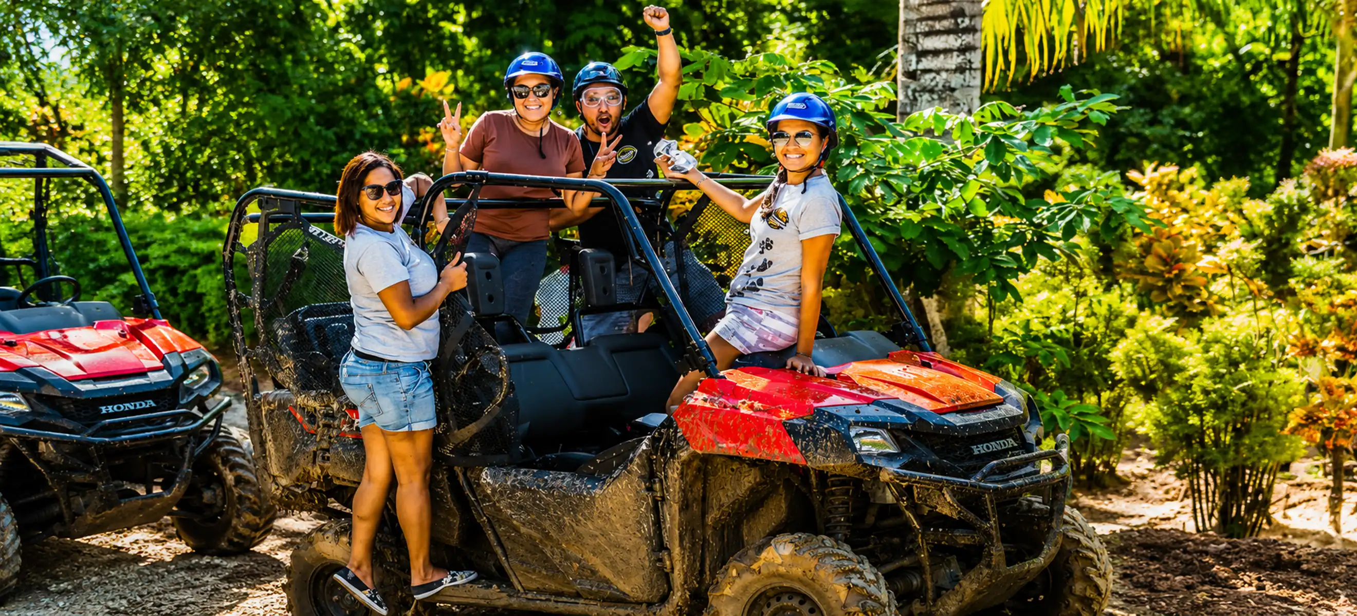 Group of friends posing with a mud-covered 4x4 jungle buggy during the Monkeyland & Jungle Buggies Punta Cana adventure, an exciting off-road eco tour in the Dominican Republic.