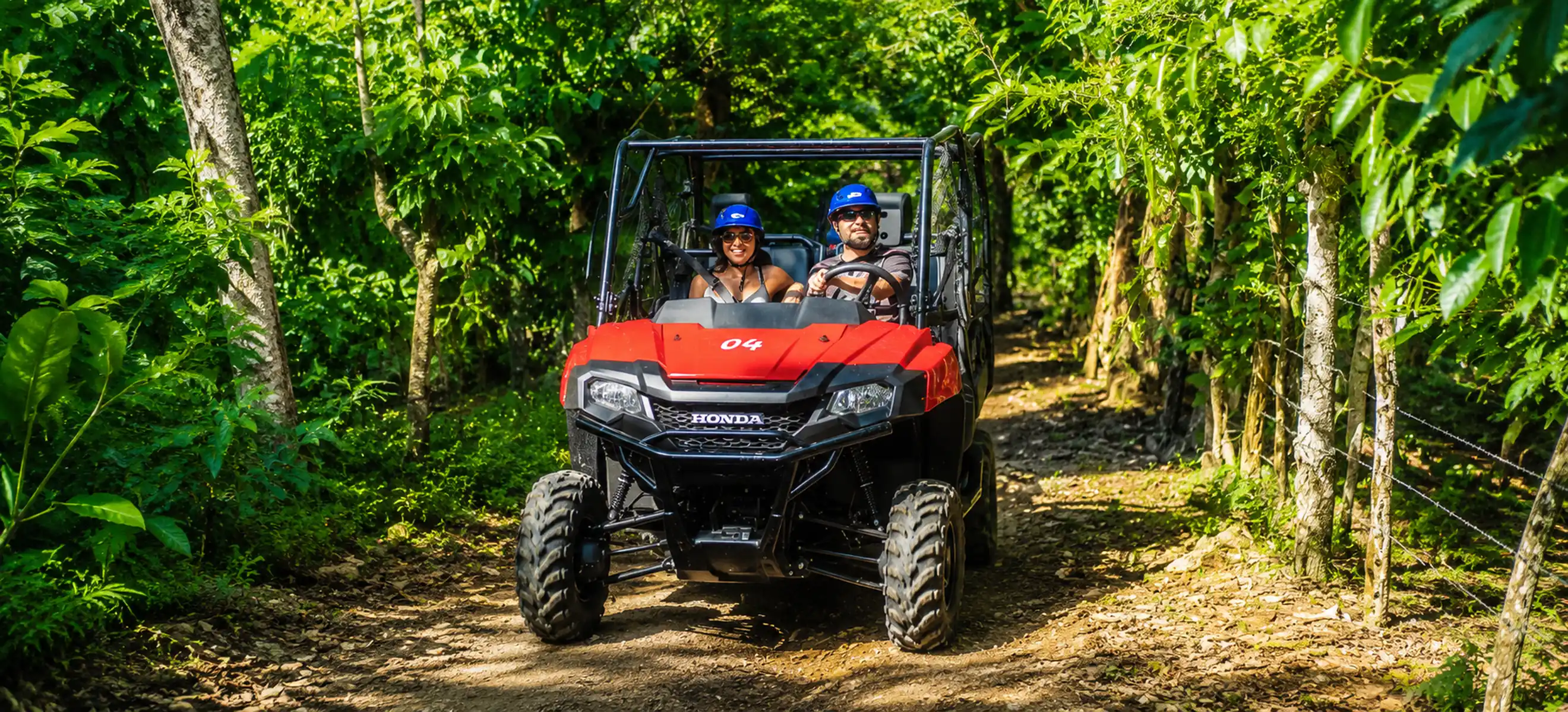 Couple driving a red 4x4 jungle buggy through lush tropical forest trails during the Monkeyland & Jungle Buggies Punta Cana adventure, one of the top off-road excursions in the Dominican Republic