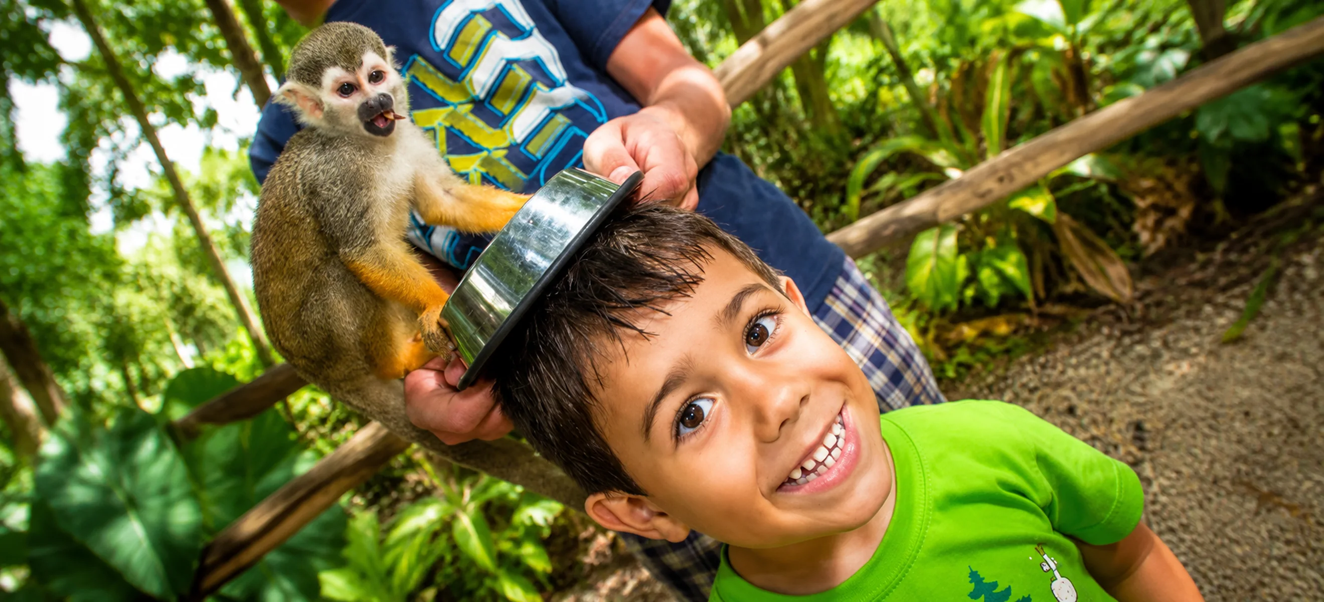 Smiling child enjoying a close interaction with a friendly squirrel monkey during the Monkeyland Punta Cana eco adventure, one of the top family excursions in the Dominican Republic.