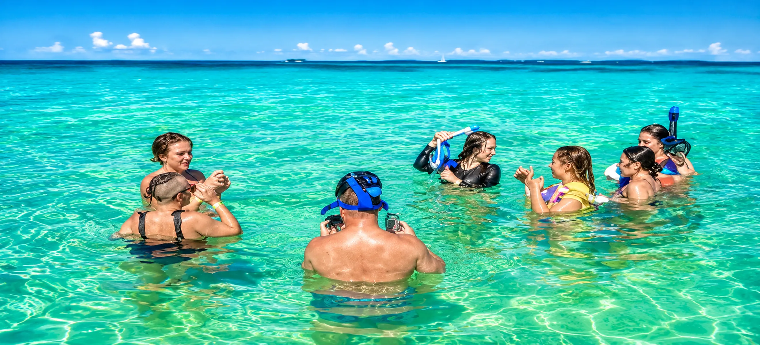 Guests snorkeling and relaxing in the crystal-clear turquoise waters of the Punta Cana Natural Pool during a Caribbean yacht and catamaran excursion in the Dominican Republic.